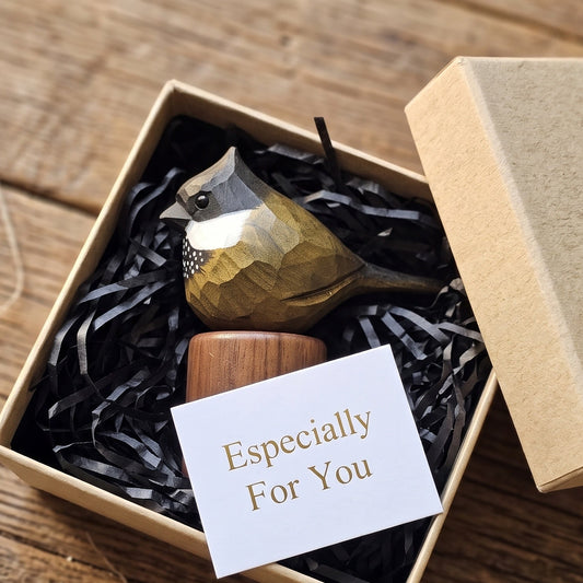 A small Eastern Whipbird in a geometric wood-fiber finish sits in a kraft gift box with black shredded paper filler, a wooden base, and a white card reading 'Especially For You,' photographed on a rustic wooden surface.