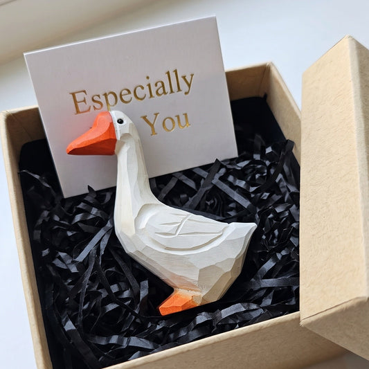 A white geometric goose figurine with orange beak and feet, displayed inside a kraft gift box with black shredded paper and a card that reads 'Especially You'.