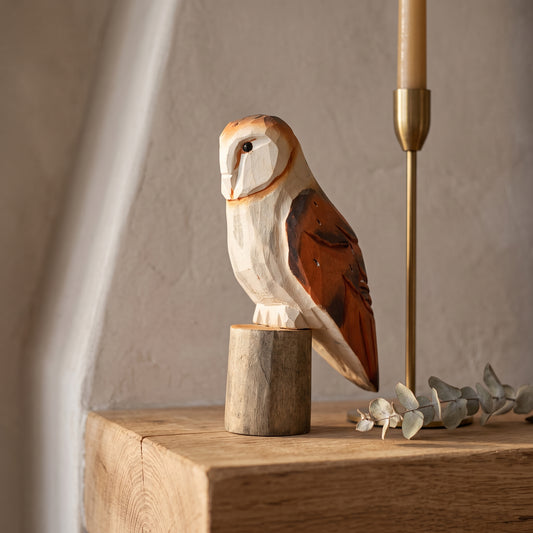 Handcrafted wooden American Barn Owl statue on a rustic wooden mantel with brass candlestick and dried eucalyptus