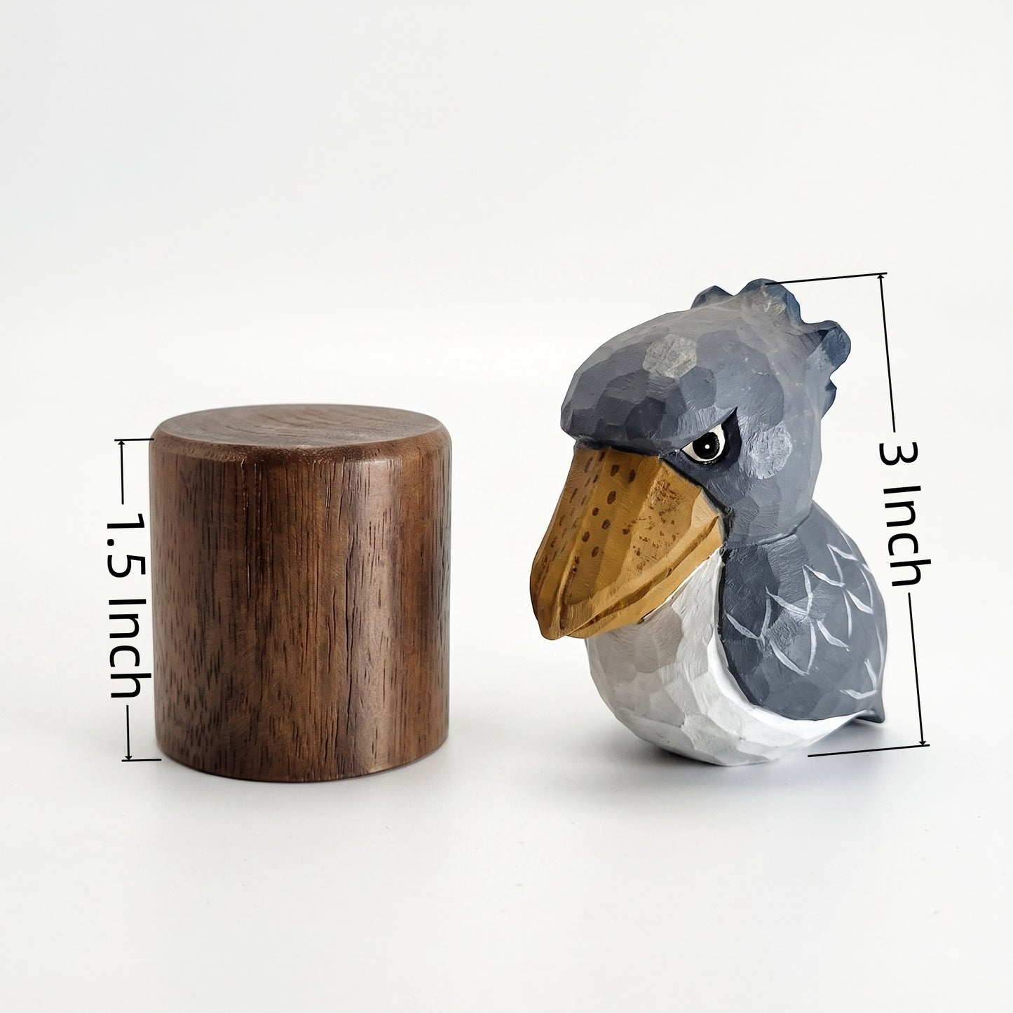 A small carved Baby Shoebill figurine shown next to a wooden cylinder on a white background, with dimension labels indicating the bird is 3 inches tall and the cylinder is 1.5 inches wide.