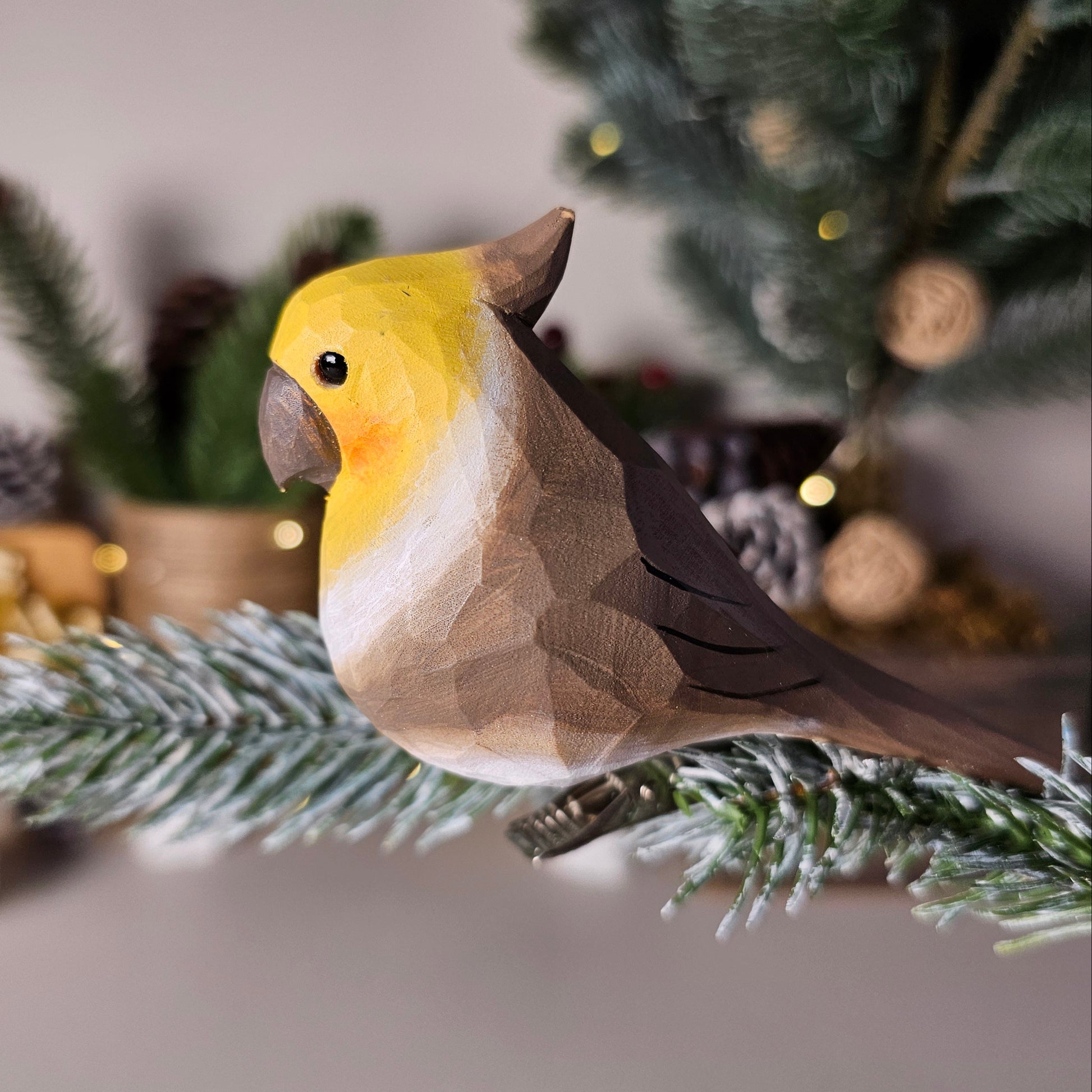 Hand-carved white cockatiel clip-on bird ornament perched on a pine branch