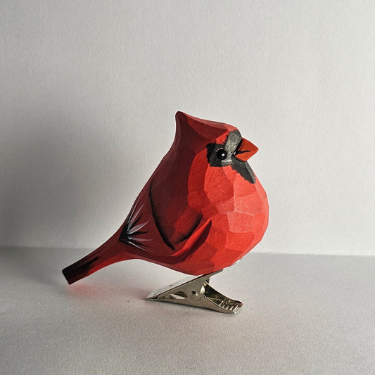 Hand-carved red wooden male cardinal clip-on ornament standing on a plain white surface.
