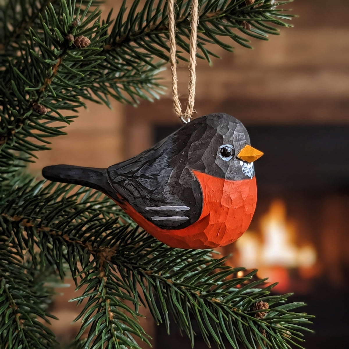 Hand-carved wooden American Robin ornament hanging on a pine tree branch.