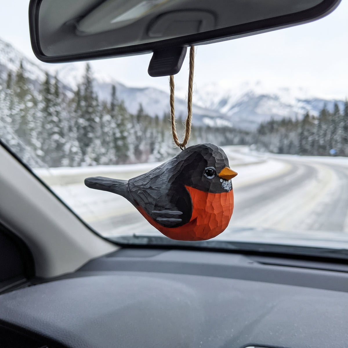 Hand-carved wooden American Robin ornament hanging from a car rearview mirror.