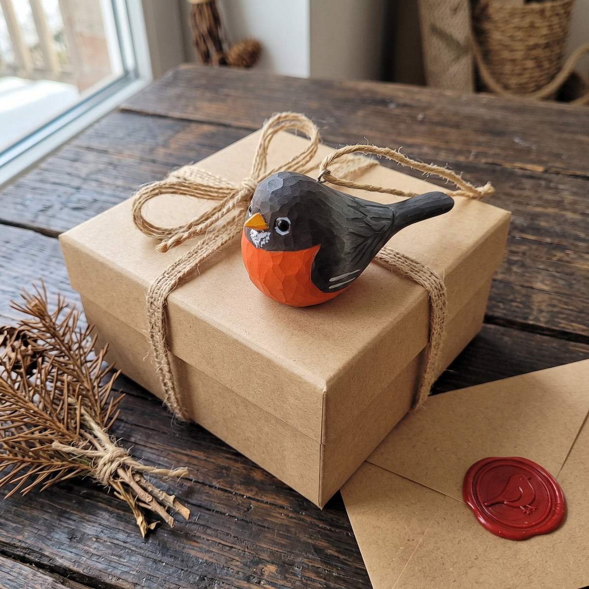 Hand-carved wooden American Robin ornament resting on a twine-tied gift box.