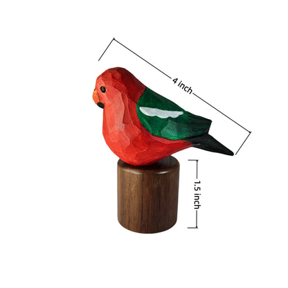 A small carved  Australian King Parrot figurine with a red body, green wing, black tail, and white eye patch, mounted on a dark wooden base. Measurement lines and text indicate dimensions: 4 inch length and 1.