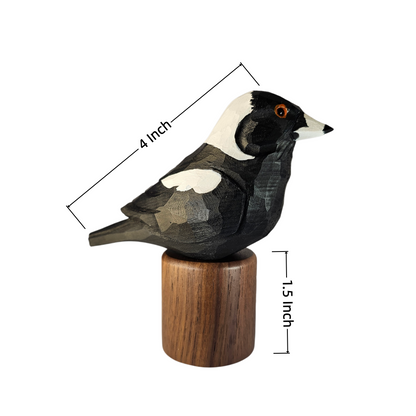 A carved wooden Australian Magpie figurine with black, white, and gray tones perched on a cylindrical wooden base, shown on a white background with dimension lines indicating 4 inch length, 1.5 inch height, and the base width.