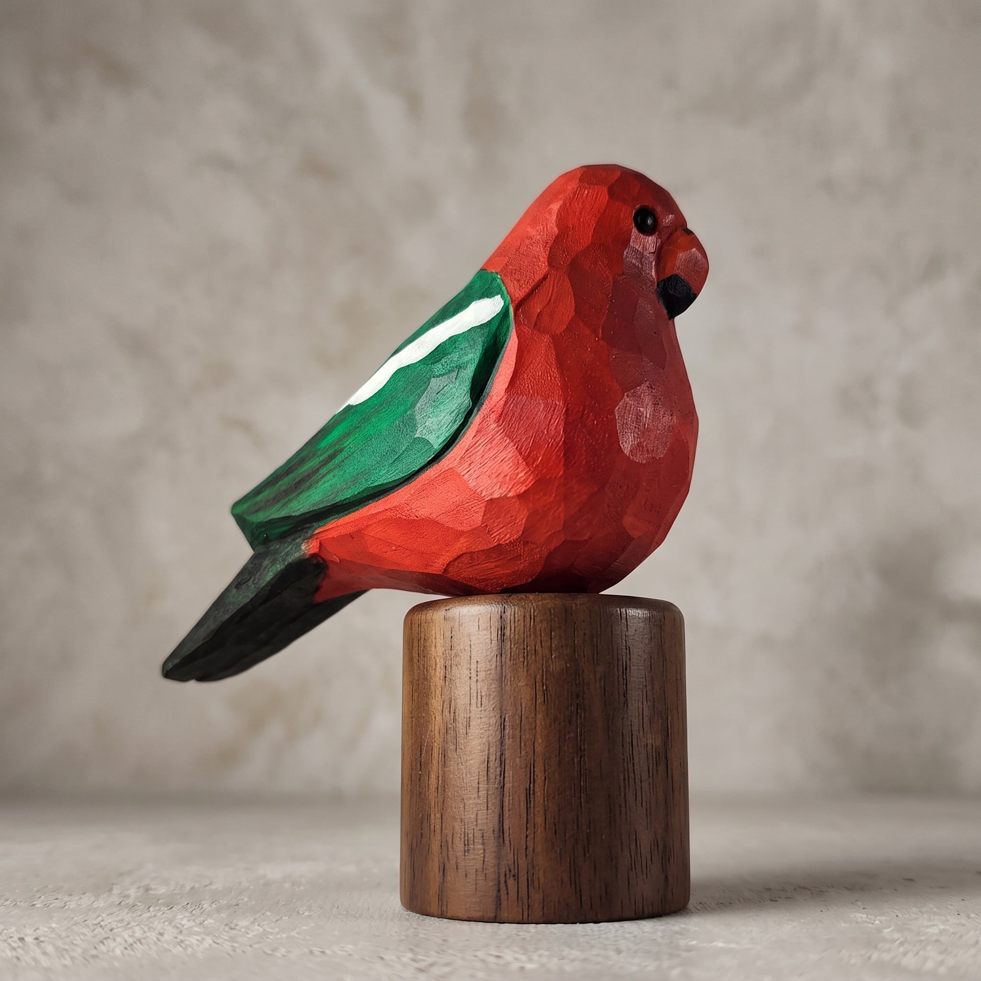 Side profile of a hand-carved wooden Australian King Parrot figurine with a vibrant red body, green wing, and black tail, mounted on a solid Black Walnut cylinder base.