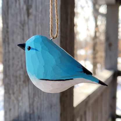Hand-carved wooden bluebird hanging ornament with twine loop outdoors