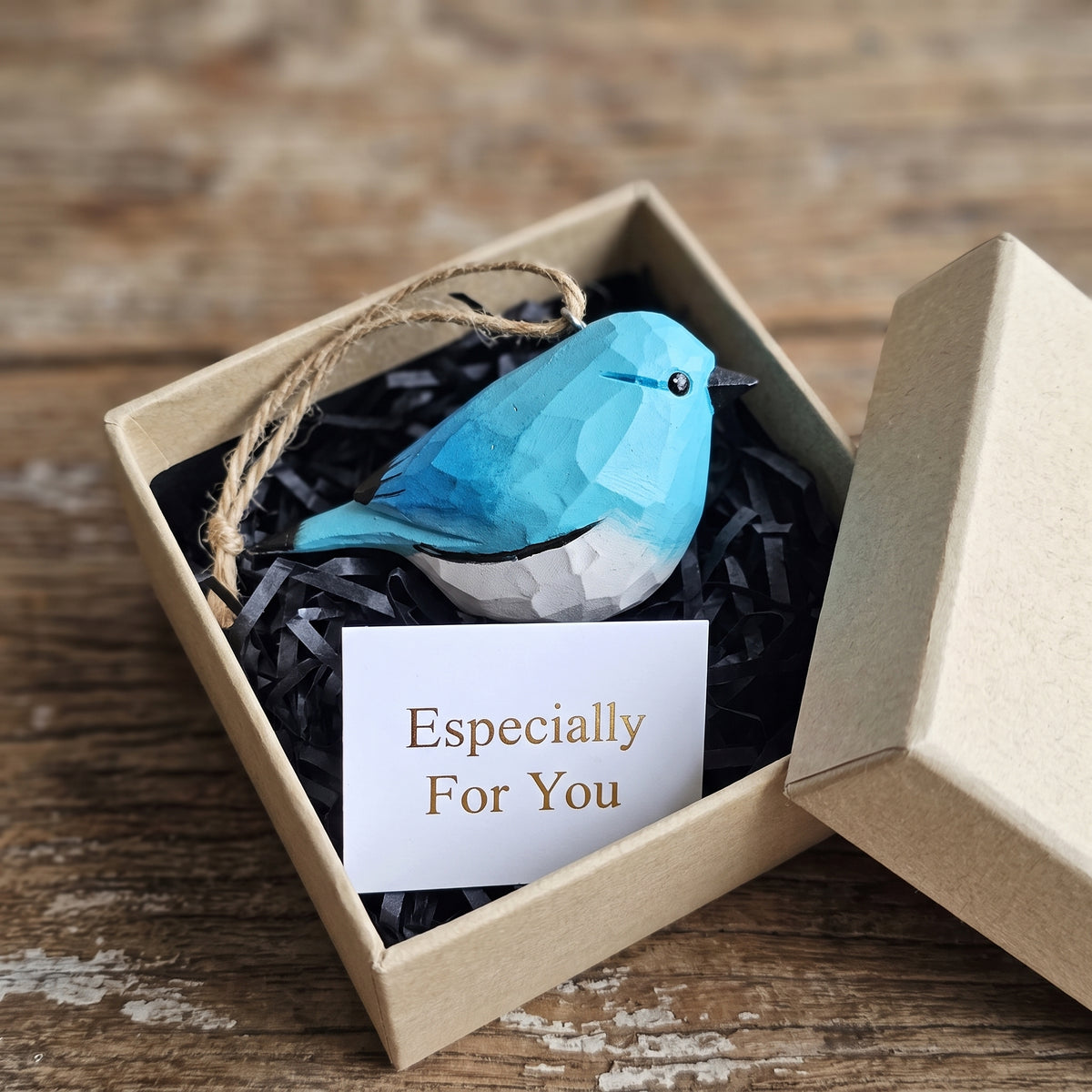 Hand-carved wooden bluebird ornament packaged inside a kraft gift box with an "Especially For You" card