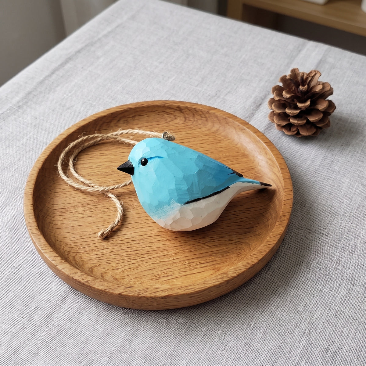 Hand-carved wooden bluebird ornament with a coiled jute cord resting on a round wooden tray
