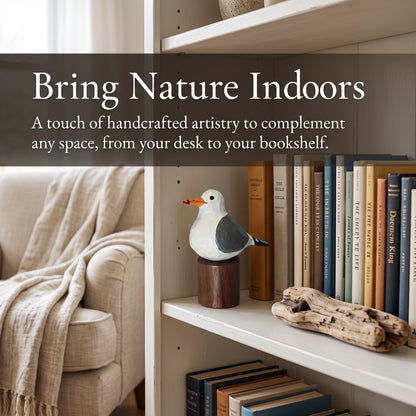 A handcrafted California gull figurine on a wooden base displayed on a white bookshelf next to books and driftwood, with a beige armchair and throw blanket in the background. Text overlay reads: 'Bring Nature Indoors'.