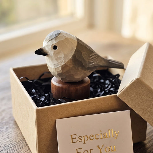 A small geometric Canada jay figurine displayed in an open kraft gift box with black paper filler and a card that reads 'Especially For You.' The scene is placed on a wooden surface near a softly blurred window.