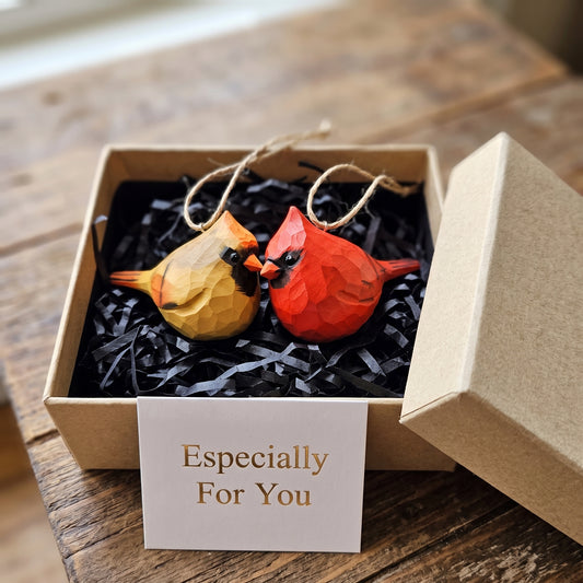 Two geometric wooden cardinal ornaments, one yellow and one red, displayed in a kraft gift box with black paper shred and a card that reads 'Especially For You'.