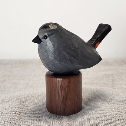 A hand-carved Gray Catbird figurine in slate-gray with a black cap, perched on a cylindrical Black Walnut base against a neutral background.