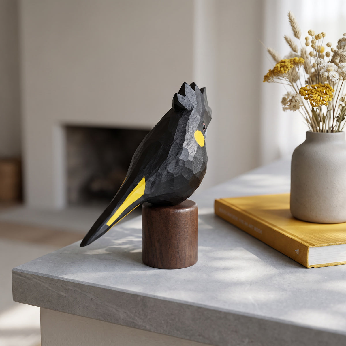 Handcrafted basswood Yellow-tailed Black Cockatoo statuette on round black walnut base in a modern home decor setting