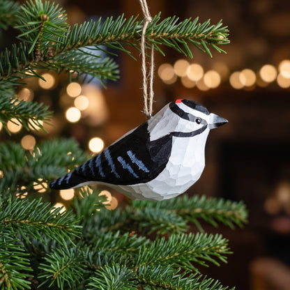 Hand-carved basswood Downy Woodpecker wooden ornament hanging on a Christmas tree branch