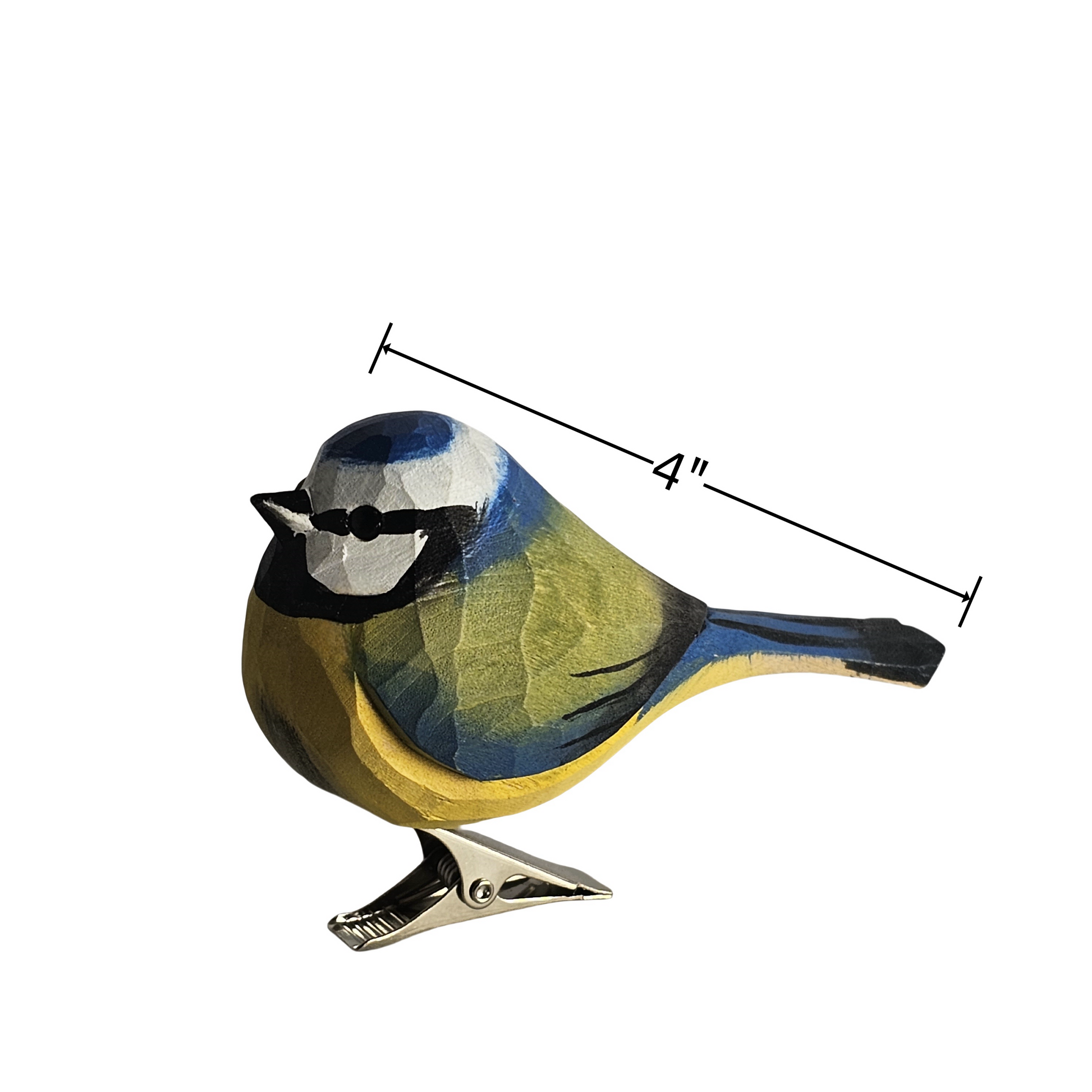 A hand-carved wooden Eurasian Blue Tit ornament shown in profile against a plain white background, featuring a vibrant blue cap, yellow breast, white cheeks, black eye-stripe, and a silver metal clip base. A black line graphic indicates its length is 4 inches.