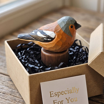 A handcrafted wooden Eurasian chaffinch figurine with a geometric low-poly design, displayed inside a brown kraft gift box with black crinkle paper filler and a card that reads 'Especially For You'.