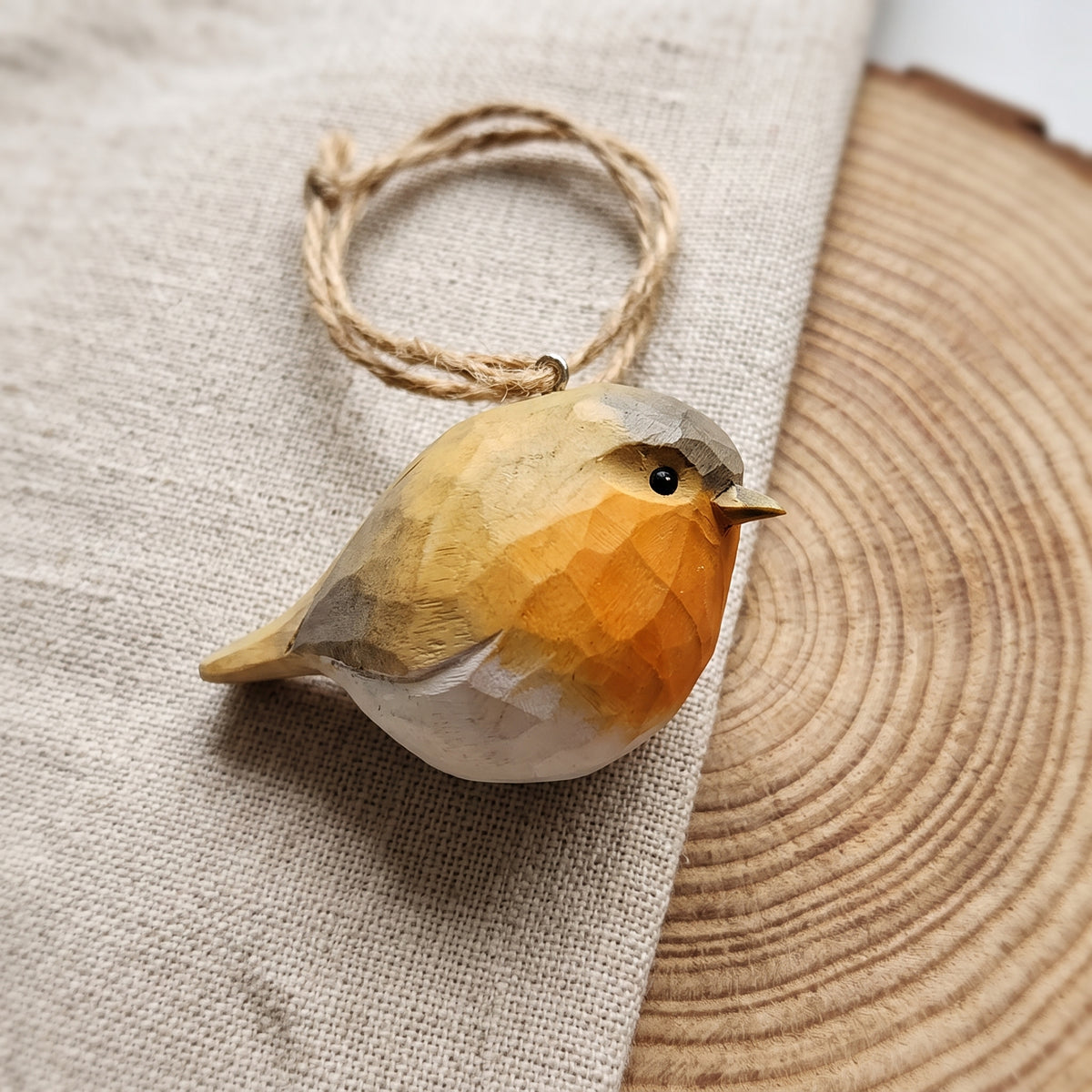 Hand-painted basswood European robin bird ornament with twine loop on rustic wood slice background