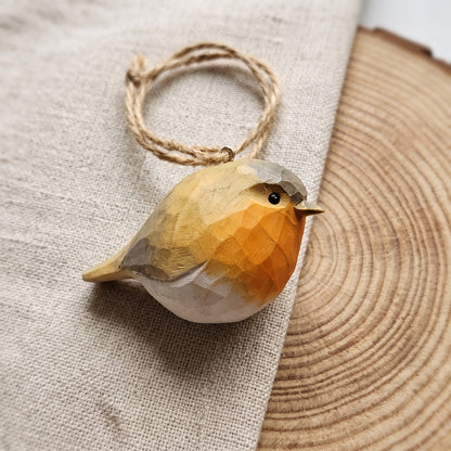 Hand-painted basswood European robin bird ornament with twine loop on rustic wood slice background