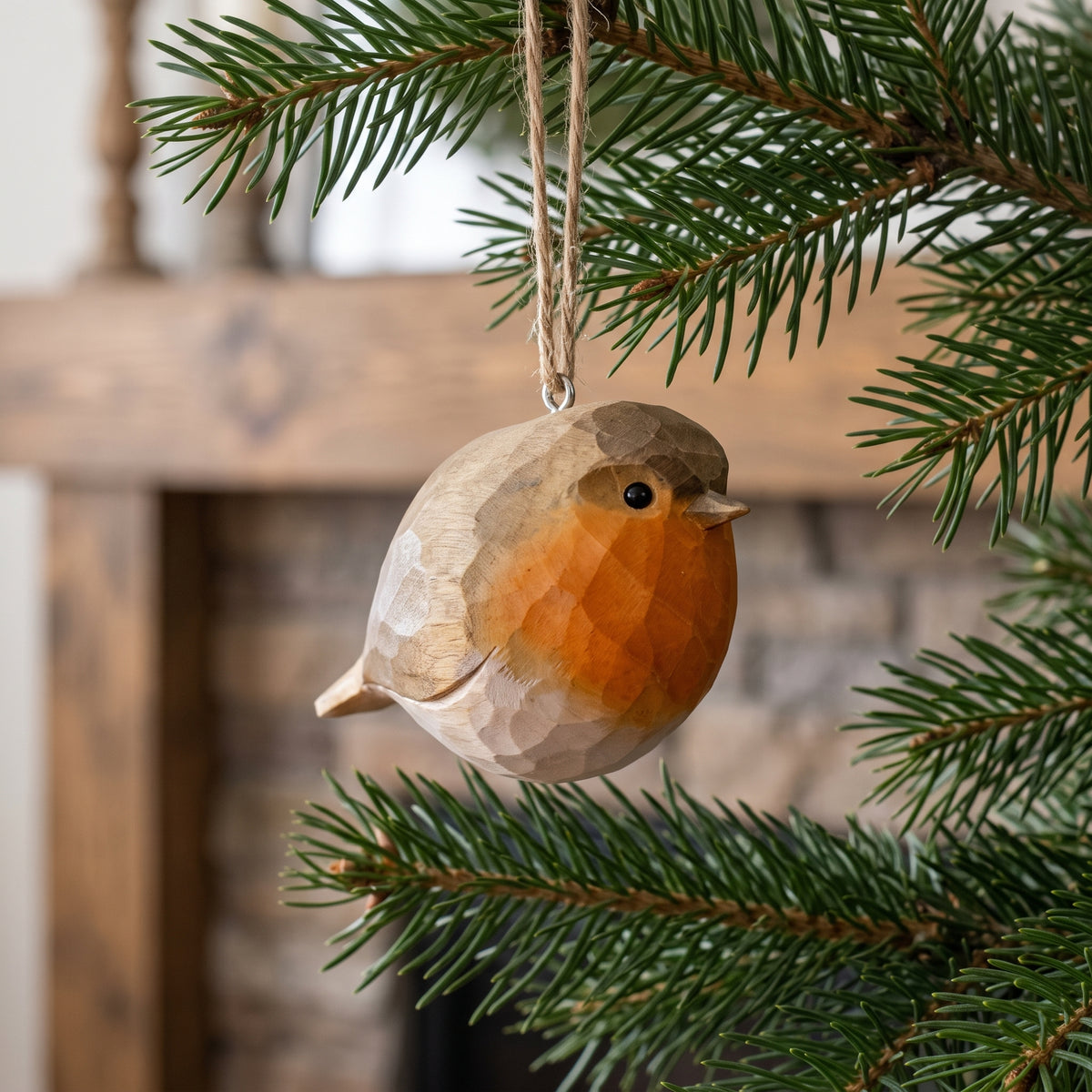 Hand-painted basswood European robin bird ornament hanging on a pine tree branch with a warm, rustic background