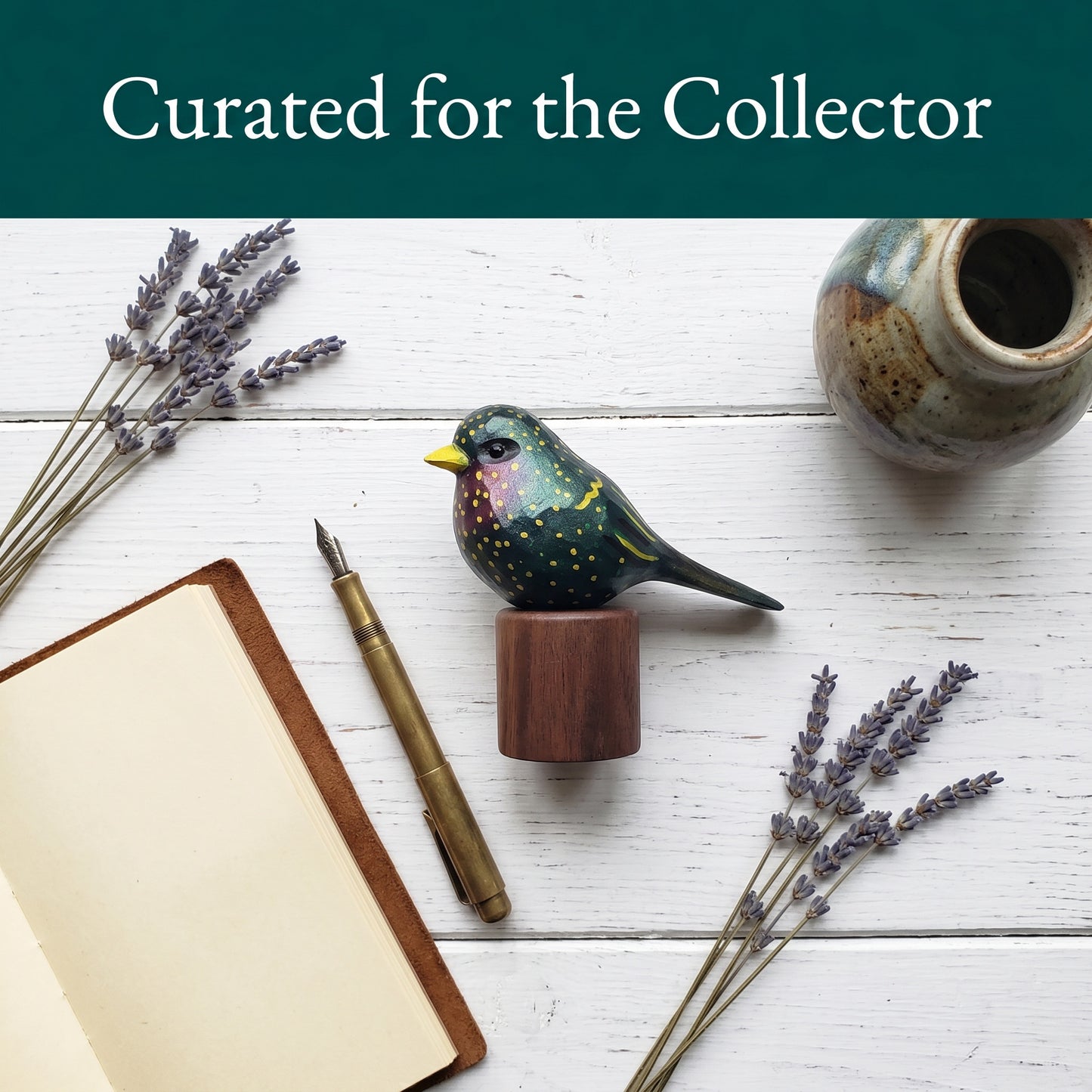 Hand-carved wooden European Starling figurine styled on a desk with a leather journal, fountain pen, and dried lavender under Curated for the Collector banner