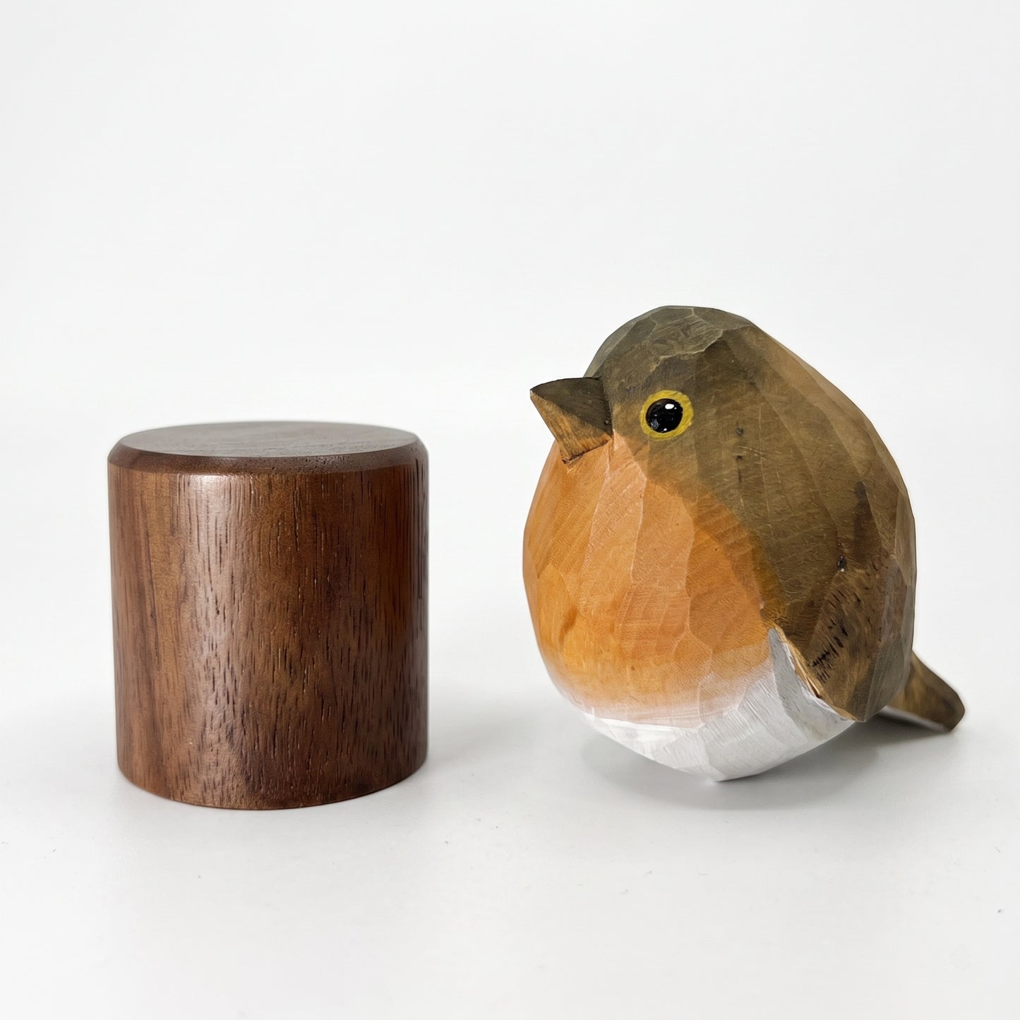 A carved wooden European robin sculpture resembling a robin, shown beside a matching cylindrical wooden lid or container on a clean white studio background.