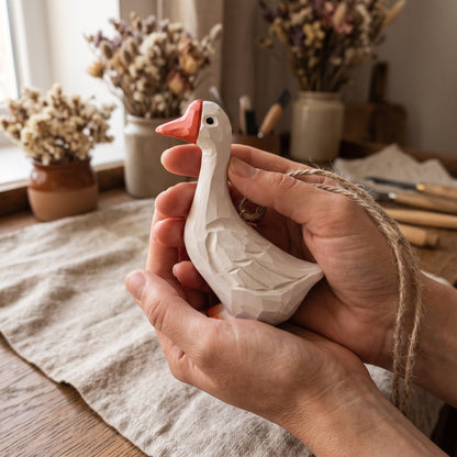 Hand-carved white goose wooden ornament held gently in two hands