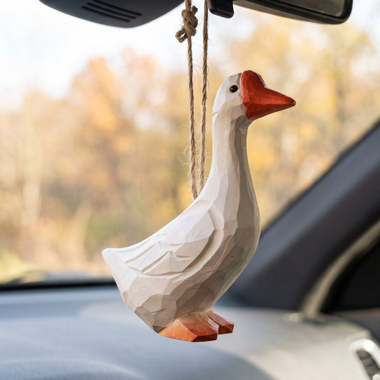 Hand-carved white goose wooden ornament hanging from a car rearview mirror