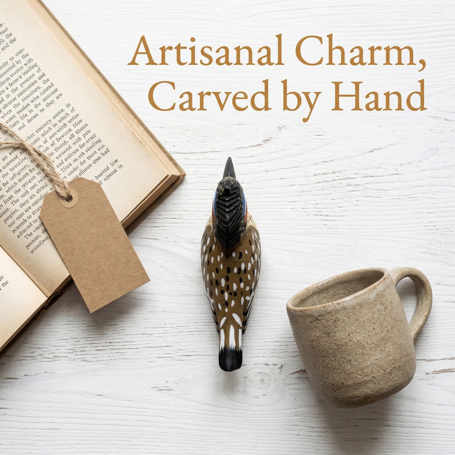 A hand-carved wooden Greater Roadrunner charm with a spotted brown, black, and white pattern sits on a white wood surface next to a beige ceramic mug and an open book with a blank tag. Text at the top reads, 'Artisanal Charm, Carved by Hand'.