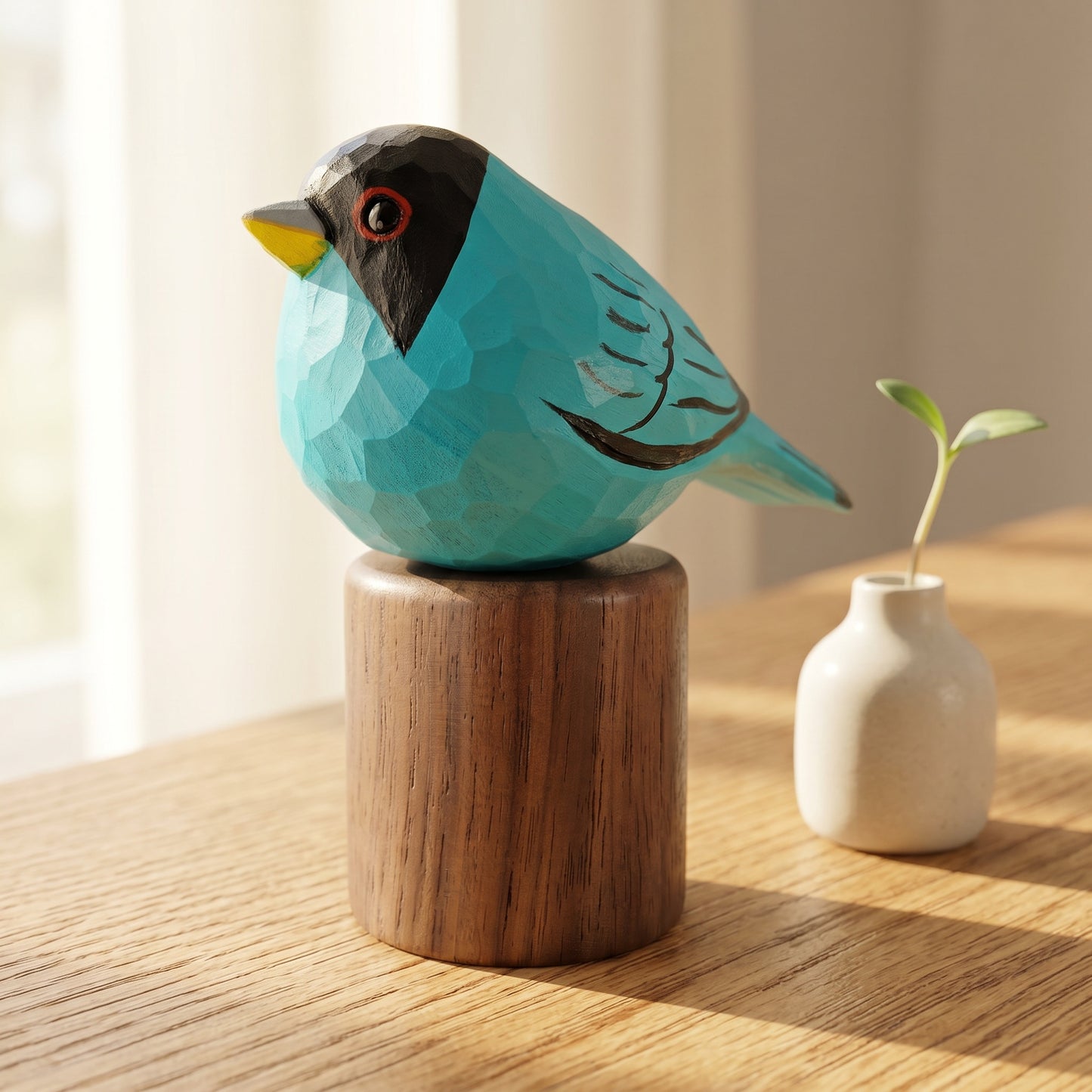 Close-up of a hand-carved turquoise Green Honeycreeper wooden bird figurine on a black walnut base next to a small white vase with a green sprout in sunlight.