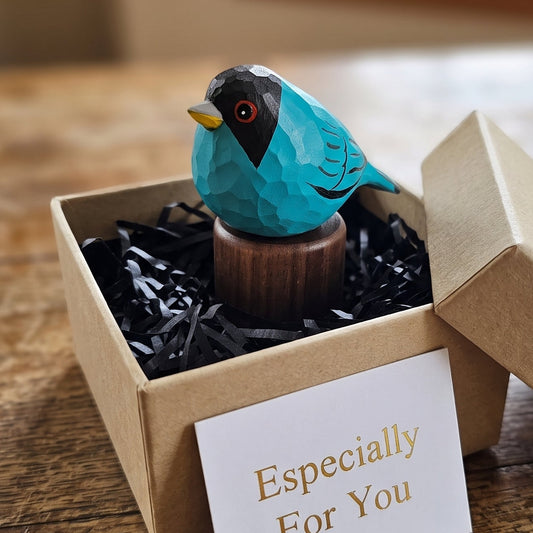 Hand-carved turquoise Green Honeycreeper wooden figurine with black walnut base nestled in a kraft gift box with black paper shredding and an "Especially For You" card.