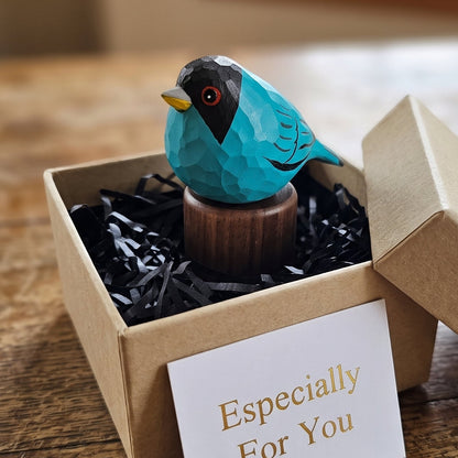 Hand-carved turquoise Green Honeycreeper wooden figurine with black walnut base nestled in a kraft gift box with black paper shredding and an "Especially For You" card.