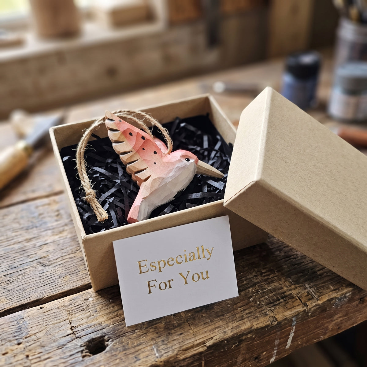 Hand-carved wooden pink hummingbird ornament packaged in a kraft gift box with an "Especially For You" card.