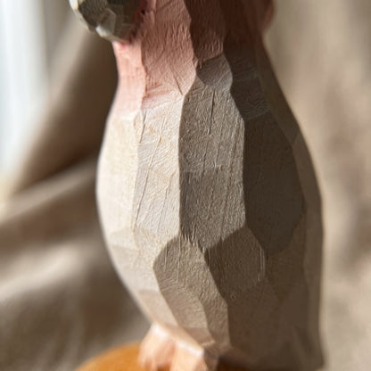 Close-up of the hand-carved wood body details on a Pink Cockatoo bird figurine, showcasing faceted knife cuts and natural grain texture.