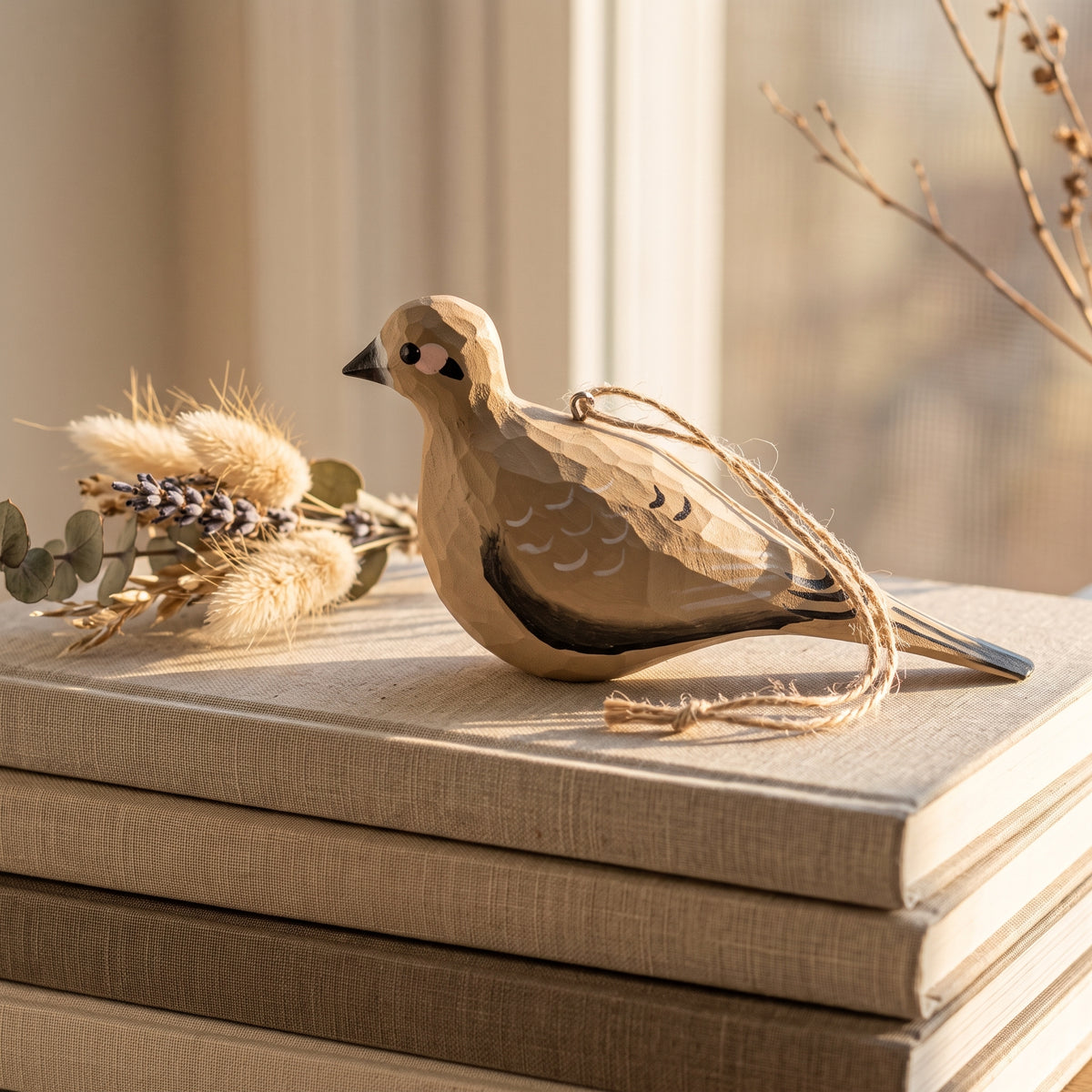 Hand-painted wooden Mourning Dove bird ornament displayed on stacked books