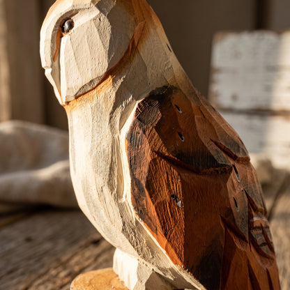 Detailed side view of hand-painted wooden barn owl statue showing carved wing texture and natural wood grain in warm sunlight