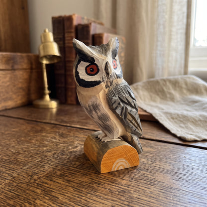 Handcrafted basswood Northern white-faced owl figurine on a natural wood log base displayed on a rustic wooden desk