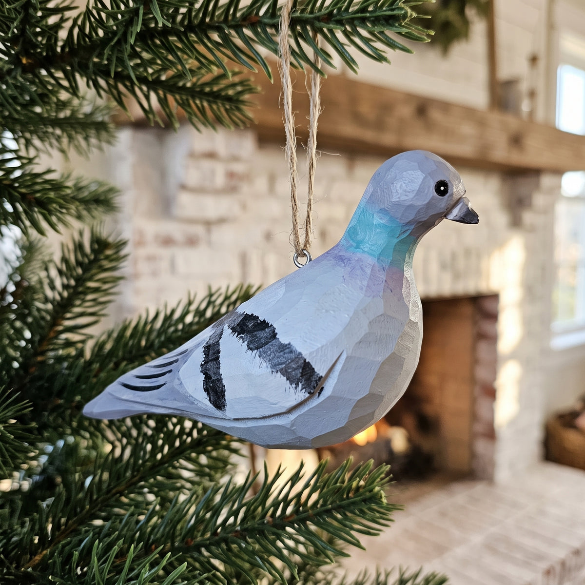 Hand-carved and hand-painted wooden Rock Dove pigeon ornament hanging from a pine tree branch.