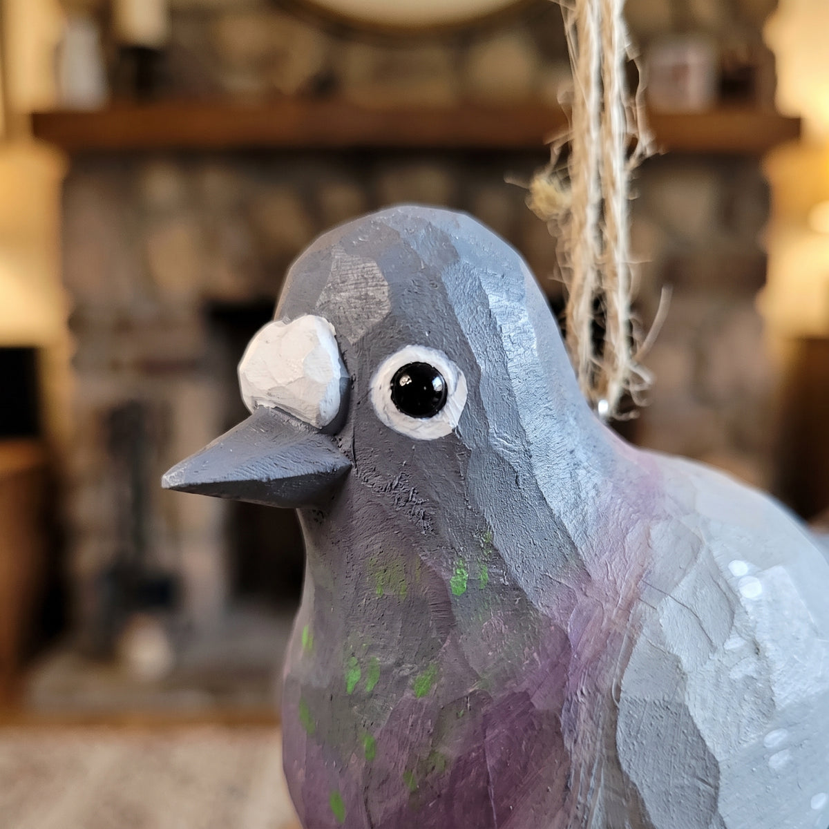 Hand-carved wooden baby pigeon hanging ornament with twine loop.