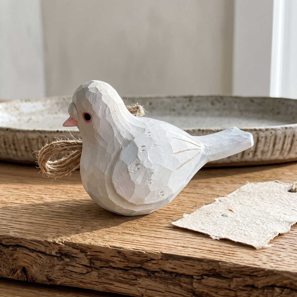 Hand-carved white wooden baby pigeon hanging ornament on a wooden surface.