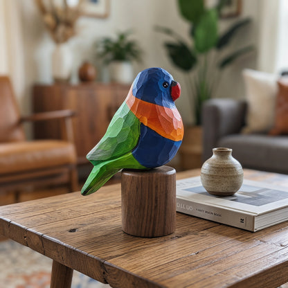 A colorful geometric wooden Rainbow lorikeet figurine with blue, green, orange, and red facets sits on a round wooden pedestal on a rustic wooden table in a cozy living room setting.