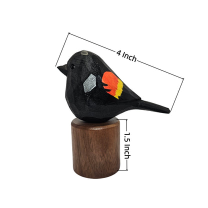 A small Red-winged blackbird figurine with painted orange, yellow, and silver details, mounted on a cylindrical wooden base. Measurement lines and text indicate the bird is 4 inches long and the base is 1.