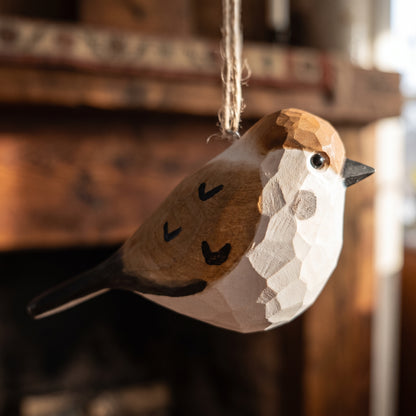 Close-up of hand-carved basswood sparrow ornament showing hand-painted plumage and twine hanging loop