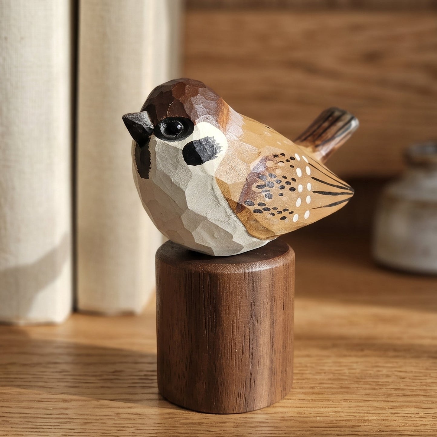 A small carved Sparrow figurine with geometric facets in brown, beige, and black, mounted on a cylindrical wooden base on a wooden shelf.