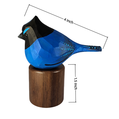 A stellers jay sculpture with a black head and a round brown wooden base, shown on a white background with dimension lines indicating 4 inch length and 15 inch height.