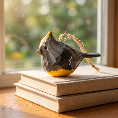 Hand-carved wooden Sultan Tit bird ornament resting on top of a stack of books by a sunny window