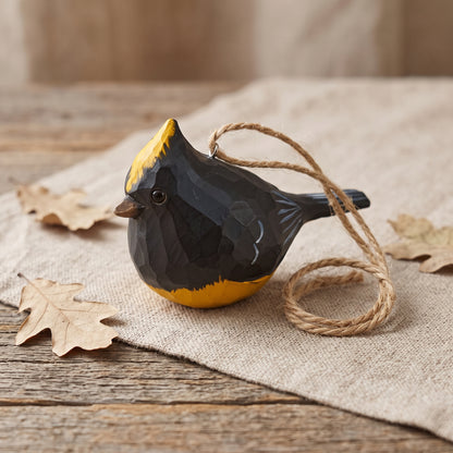 Hand-carved wooden Sultan Tit bird ornament resting on a linen cloth with dry oak leaves and coiled jute twine