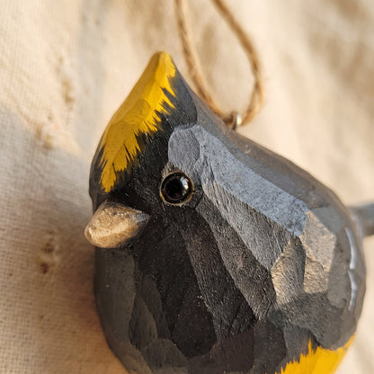 Extreme close-up of hand-carved wood details and yellow crest on a Sultan Tit bird ornament